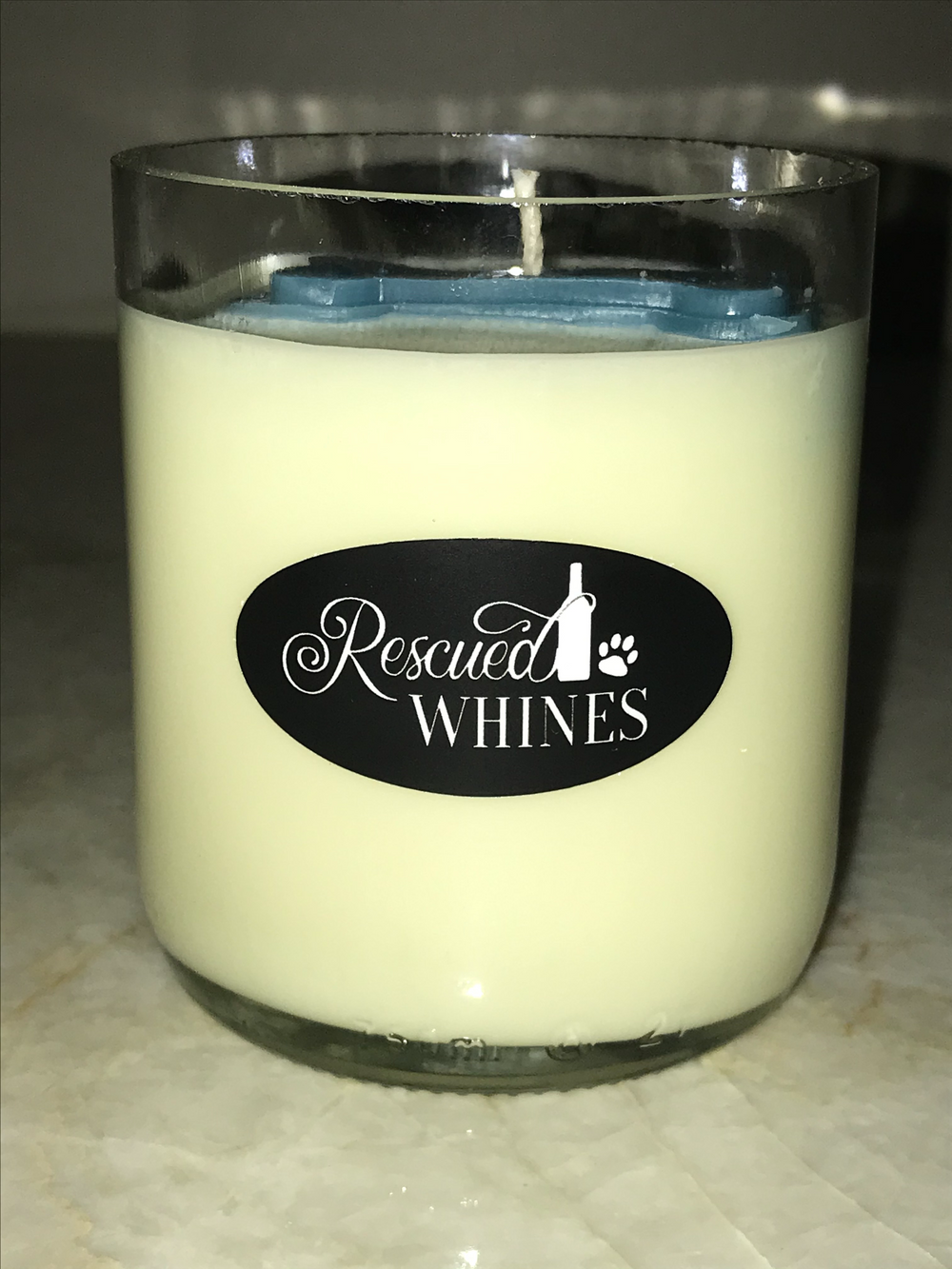 Recycled wine bottle candle in clear tumbler with embedded paw